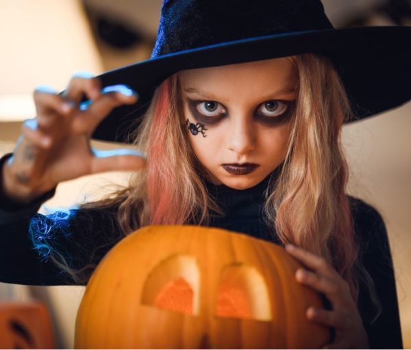 girl dressed as witch with jack-o-lantern
