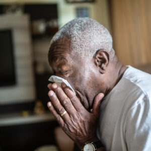 Senior man blowing his nose at home